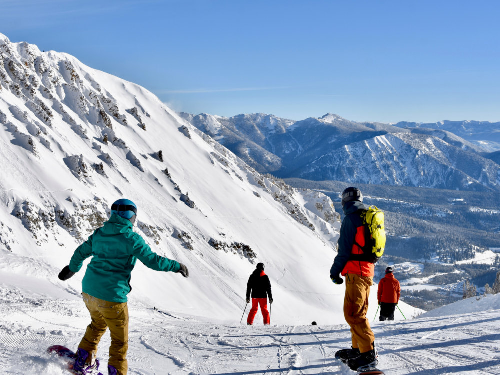 Skiers and snowboarders descending over a slope at Big Sky Ski Resort on Winter, one of the best things to do in Montana