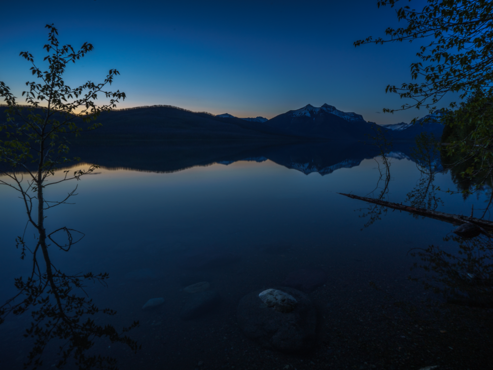 A tranquil night at Lake MacDonald, one of the best things to do in Montana, where the surrounding mountains of Glacier National Park are reflected on the still water