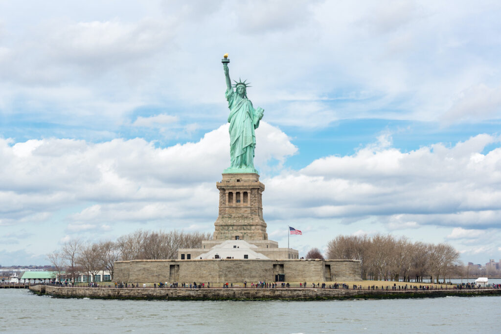 Visitors at the base of The Statue of Liberty in New York City, USA on a winter day with blue sky.